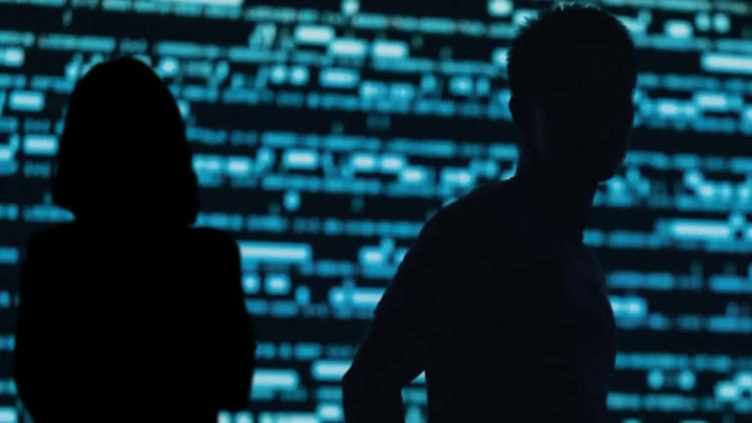 two silhouette in black in front of a background of codes in black and blue