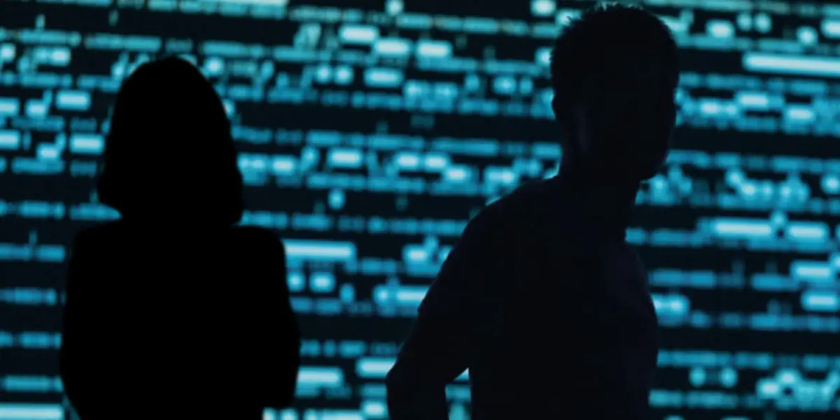 deux silhouettes noires face à un fond de code noir et bleu