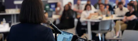 Back view of a speaker addressing a crowd. 