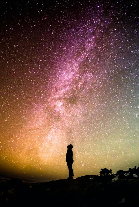 A person looks up at a starry sky. 