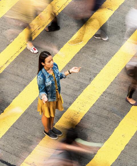 A woman in the middle of a busy crosswalk.