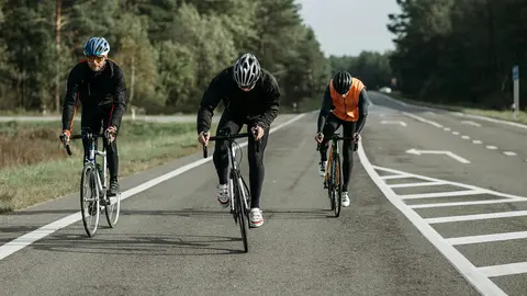 Trois cyclistes se déplacent sur une route.