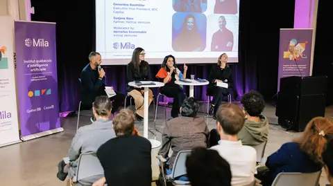 Four people addressing an audience during a panel discussion organized as part of an event.