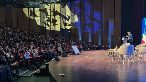 Yoshua Bengio giving a speech to a large crowd.