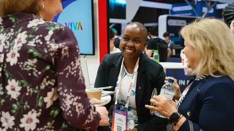Three women chat informally at a tech event. 