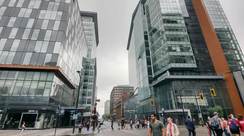 A busy urban intersection between two modern glass buildings.