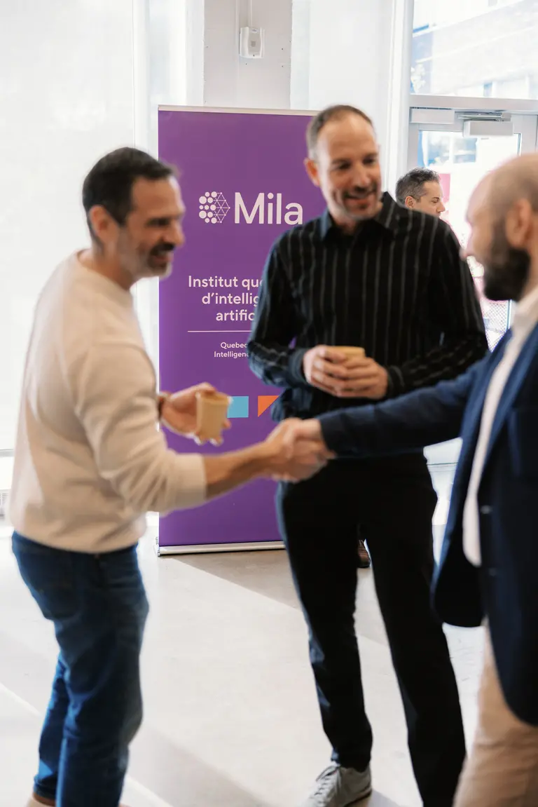 Three men talking at an event at Mila.