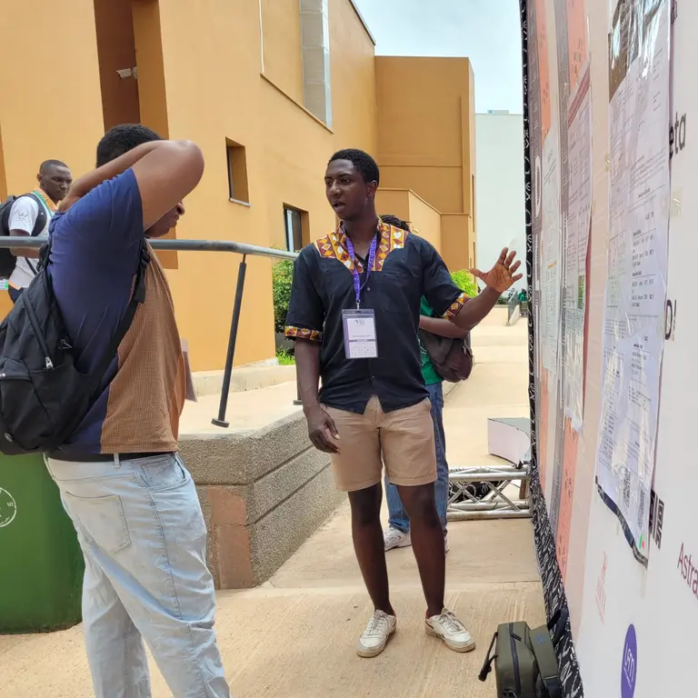 Mila researcher presenting his paper to a participant during poster session at a scientific conference