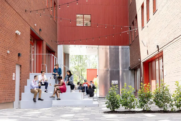 People sitting on the stairs outside the Mila building. 