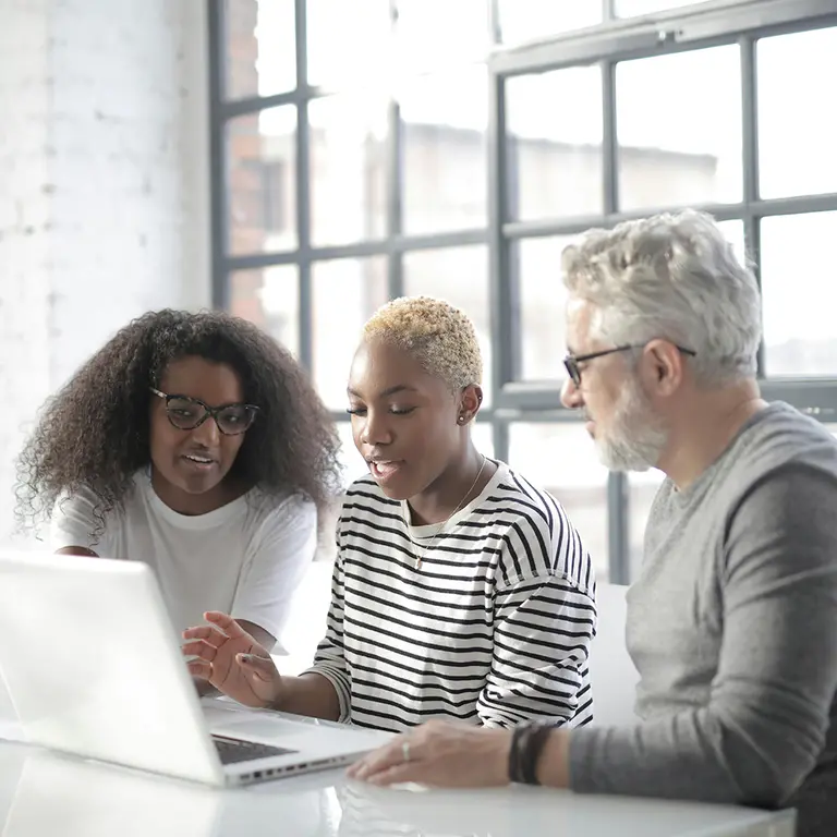 three professionals around a computer drafting a policy proposal
