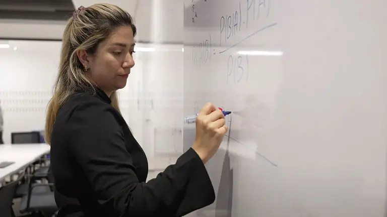 Photo de la professeure Samira A. Rahimi qui écrit sur un tableau blanc