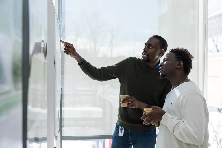 Deux chercheurs de Mila discutent d'un poster scientifique