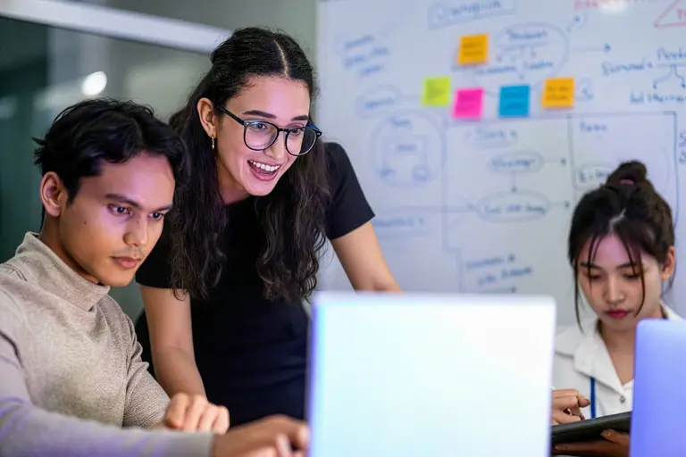 An interior shot of a collaborative workspace or office where three young professionals are working together.
