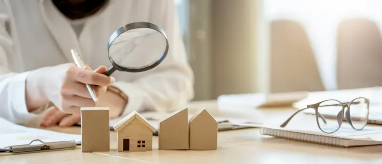 a picture of tiny box houses on a table and someone is loking at it with a lens 