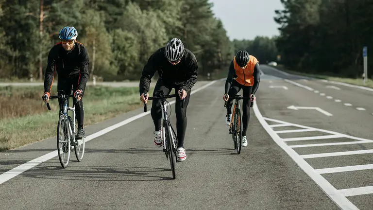 Three cyclists are moving down a road.