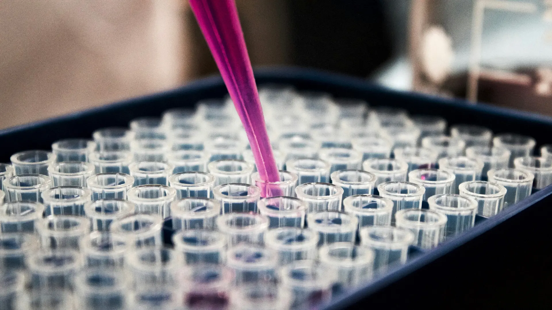 Close-up of a pipette pouring a product into a test tube.