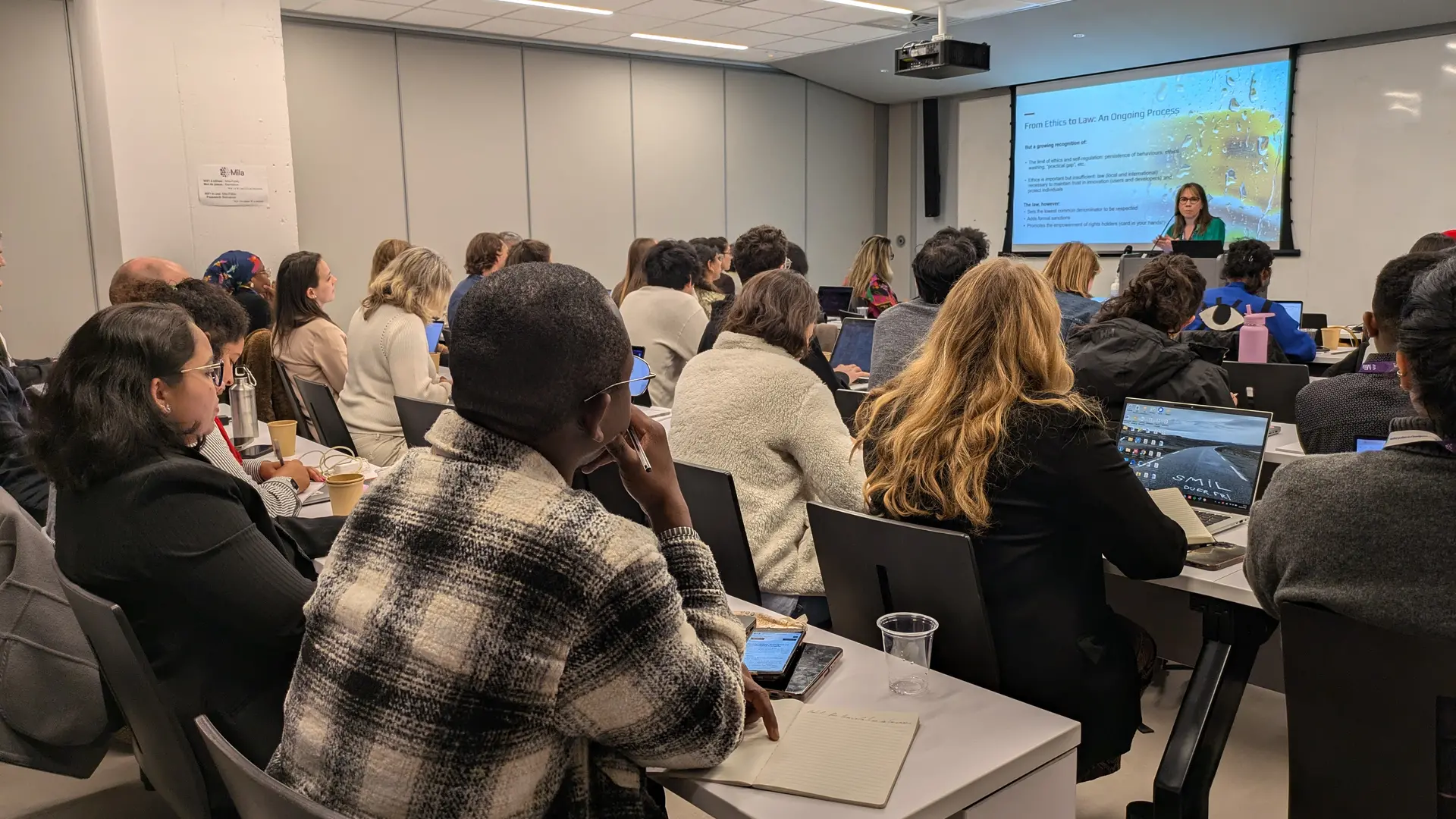 Photo de Catherine Régis donnant un cours captivant sur les droits humains dans une salle de classe remplie.