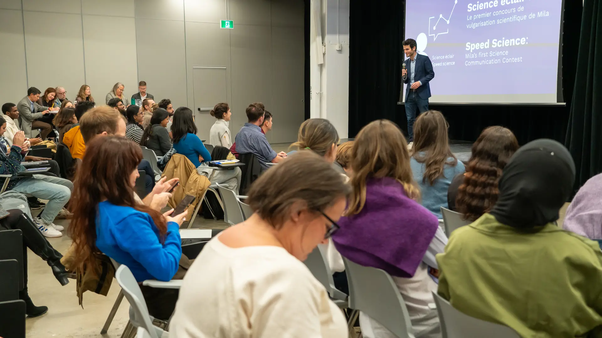 Un organisateur de l'événement explique sur scène les activités prévues pour la soirée au public.