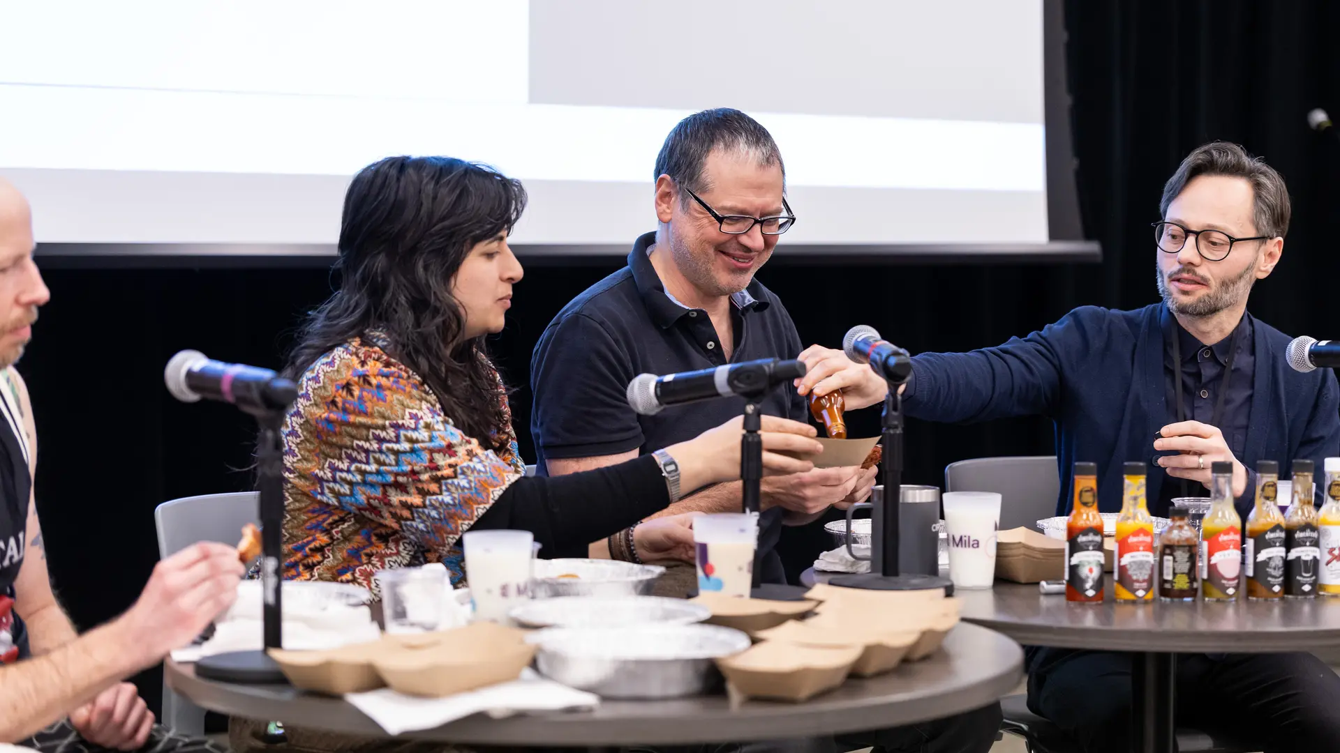 Photo des profs Blake Richards, Tegan Maharaj, Aaron Courville et Hugo Larochelle qui péparent des ailes de poulet avec de la sauce piquante en répondant à des questions