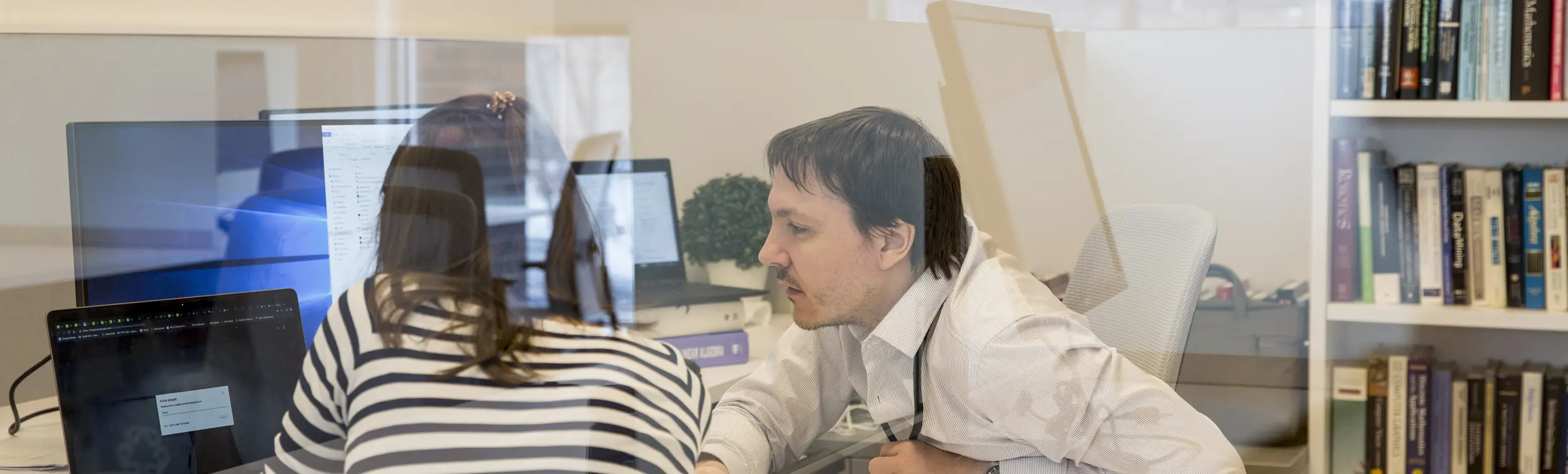 A professor and a student looking at a computer. 