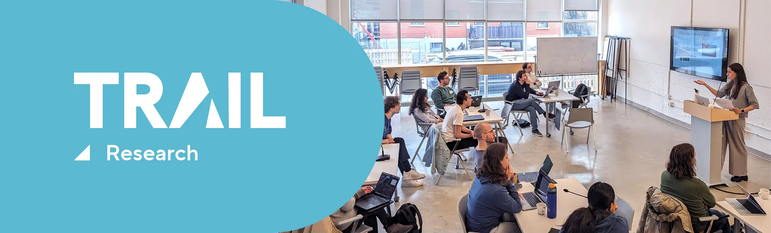 Trail research logo and a speaker in front of a classroom full of students