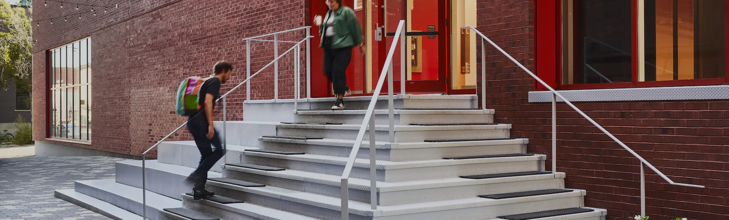 Two people walking in and out of the Mila building. 