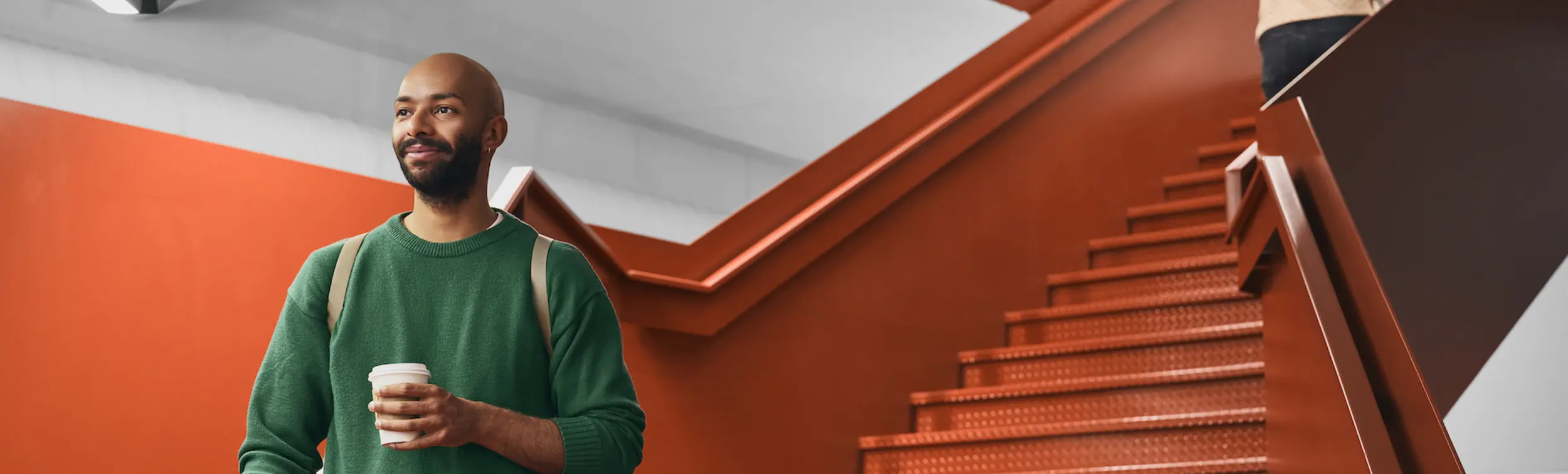 A man going down the orange stairs in Mila's premises