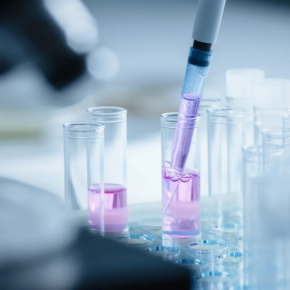 A researcher adding drops of liquid to a test tube using a micropipette.