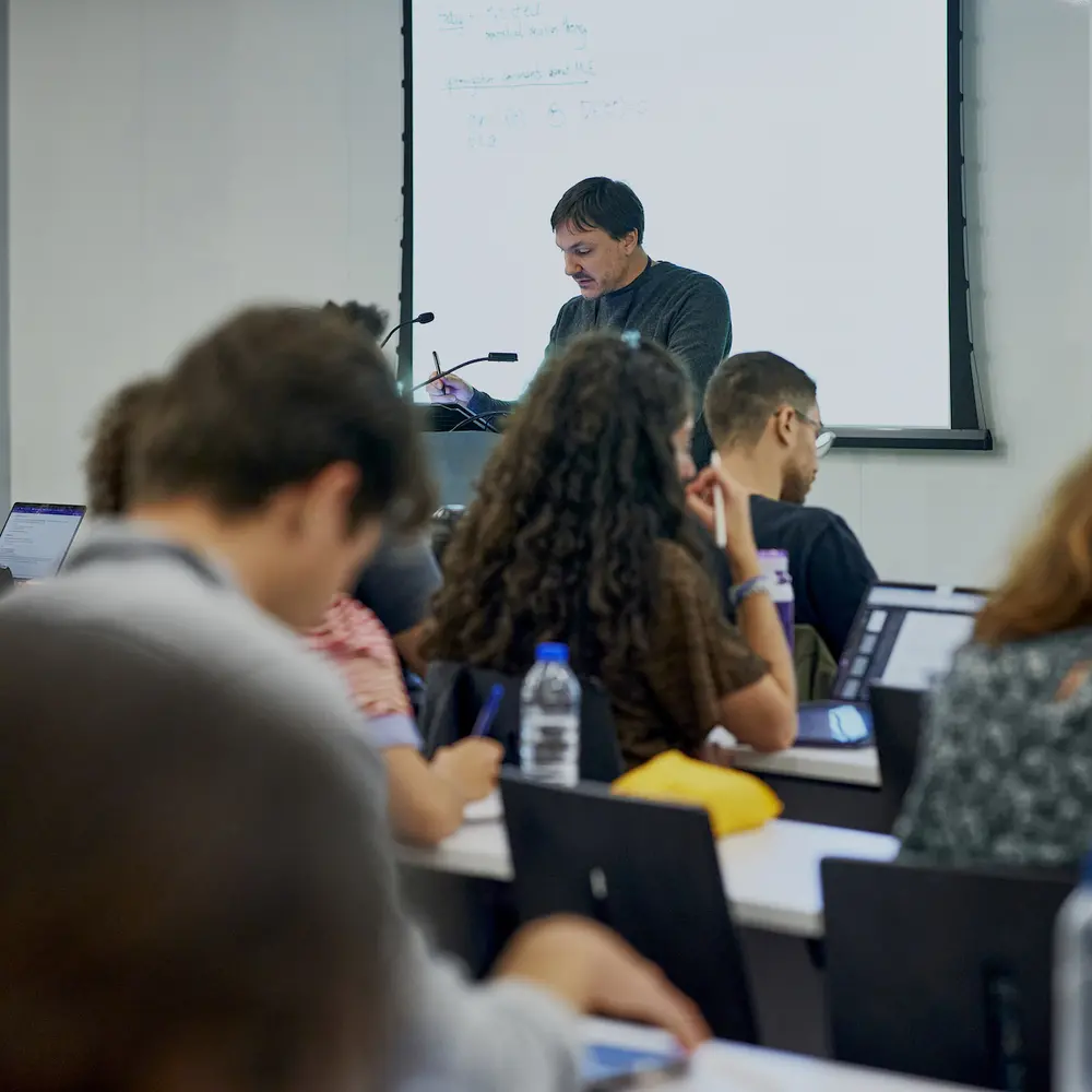 A professor lecturing in a classroom full of students.