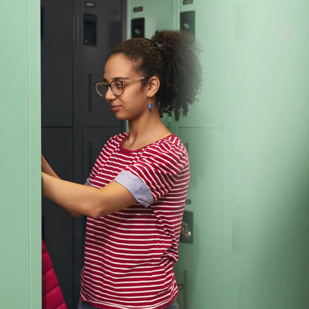 A student puts her coat away in her locker. 