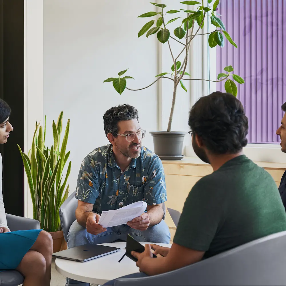 a prof and three students talking in the lounge space
