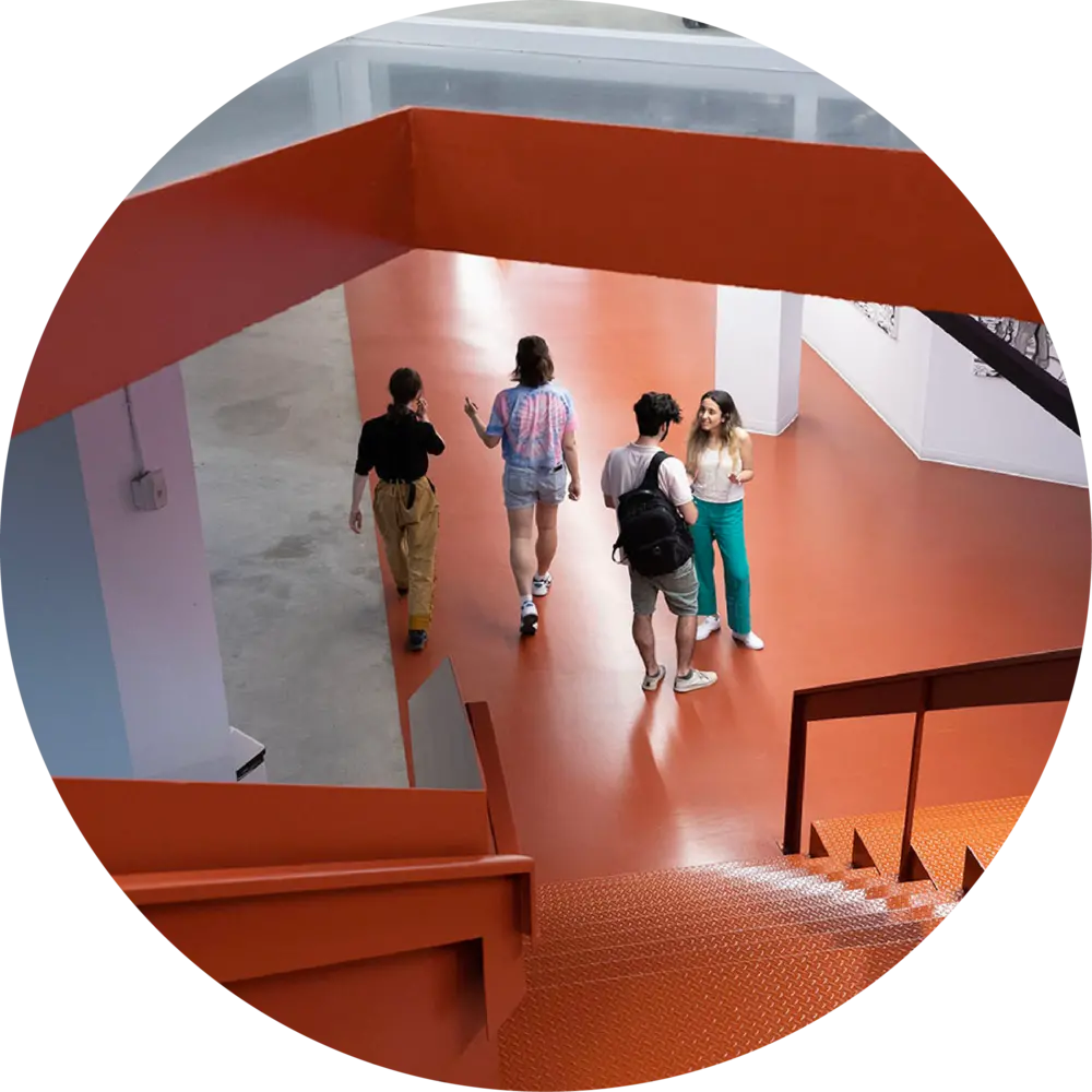 A group of students gathered at the bottom of orange stairs at Mila