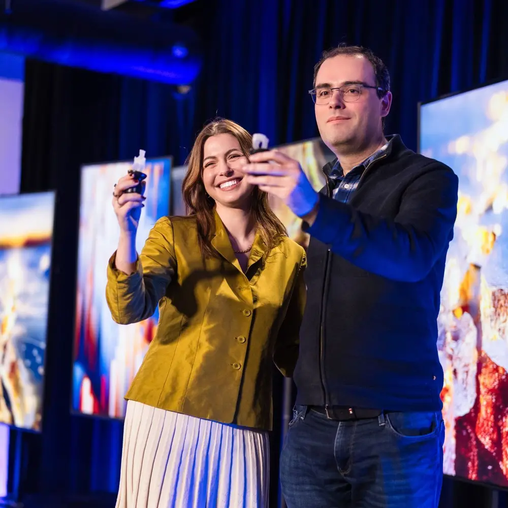 Une femme et un homme tenant leur prix tout en regardant l'appareil photo.