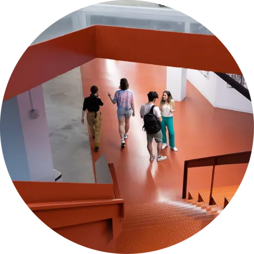 A group of students gathered at the bottom of orange stairs at Mila
