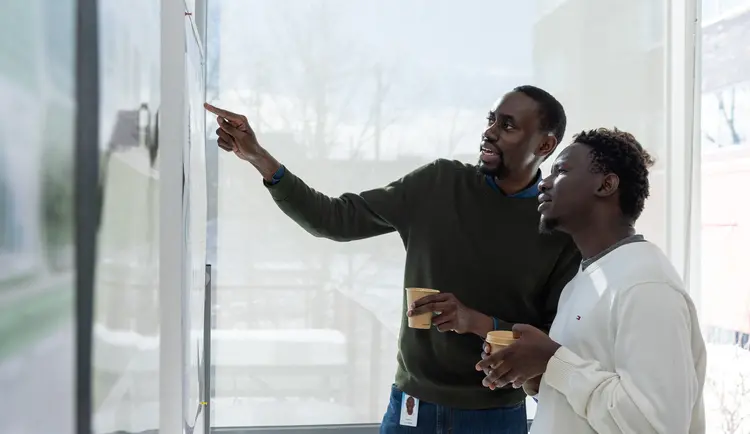 Deux chercheurs de Mila discutent d'un poster scientifique