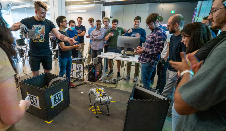 Des participants à l'école d'été en robotique essayant de déplacer un robot